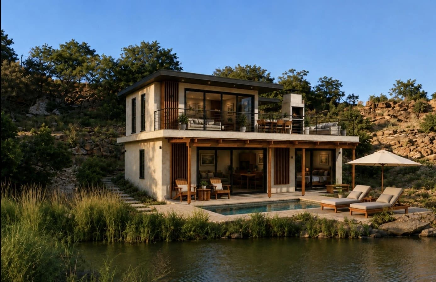 Double-storey ARTERRA precast modular home on a rocky waterside slope, with a covered veranda, upper terrace and pool